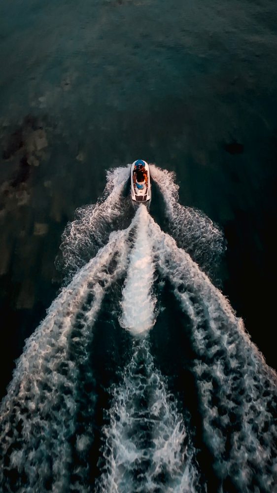 Jet ski cutting a white wake across dark water, seen from above